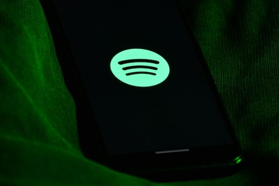 Green circle Spotify logo with black sound waves against a dark backgroun