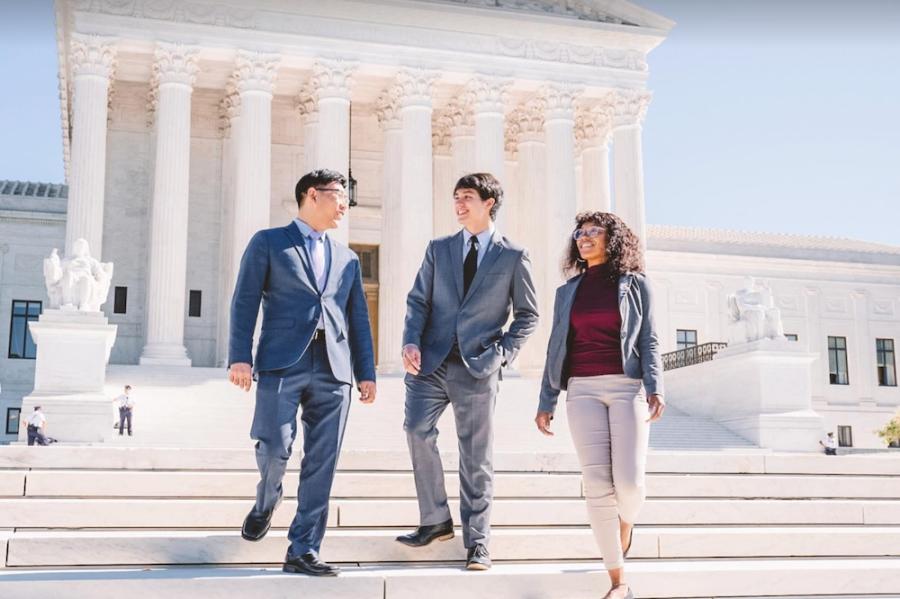Three people on the steps of a building so white it glows