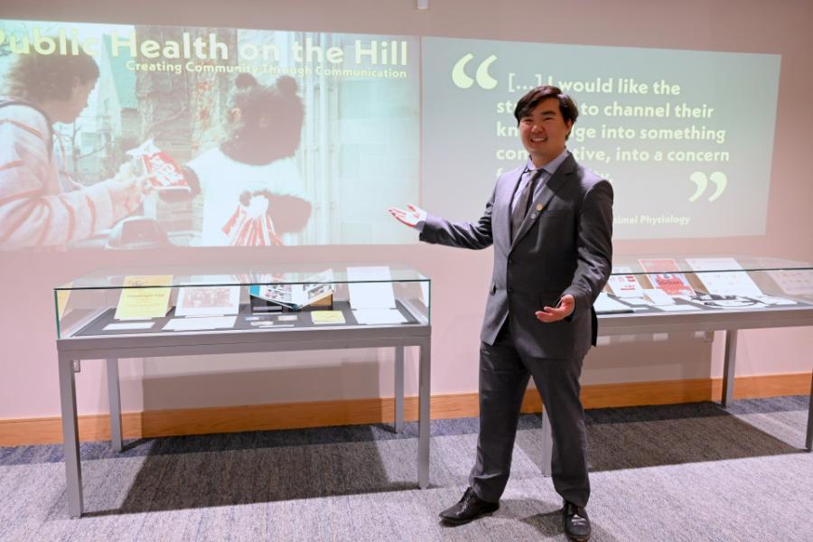Person in suit presenting a display case and an image projected on a wall
