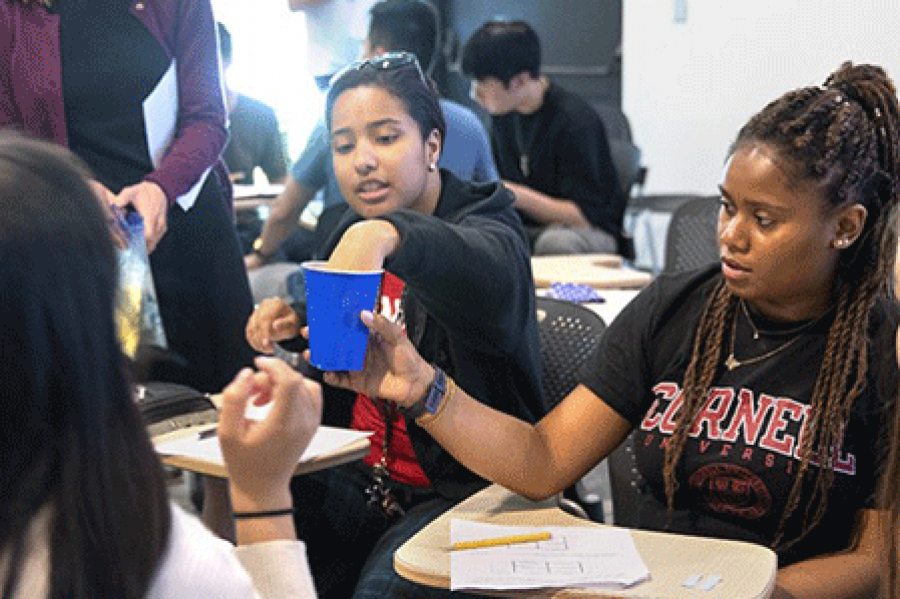  Five students in a circle with a teacher looking on