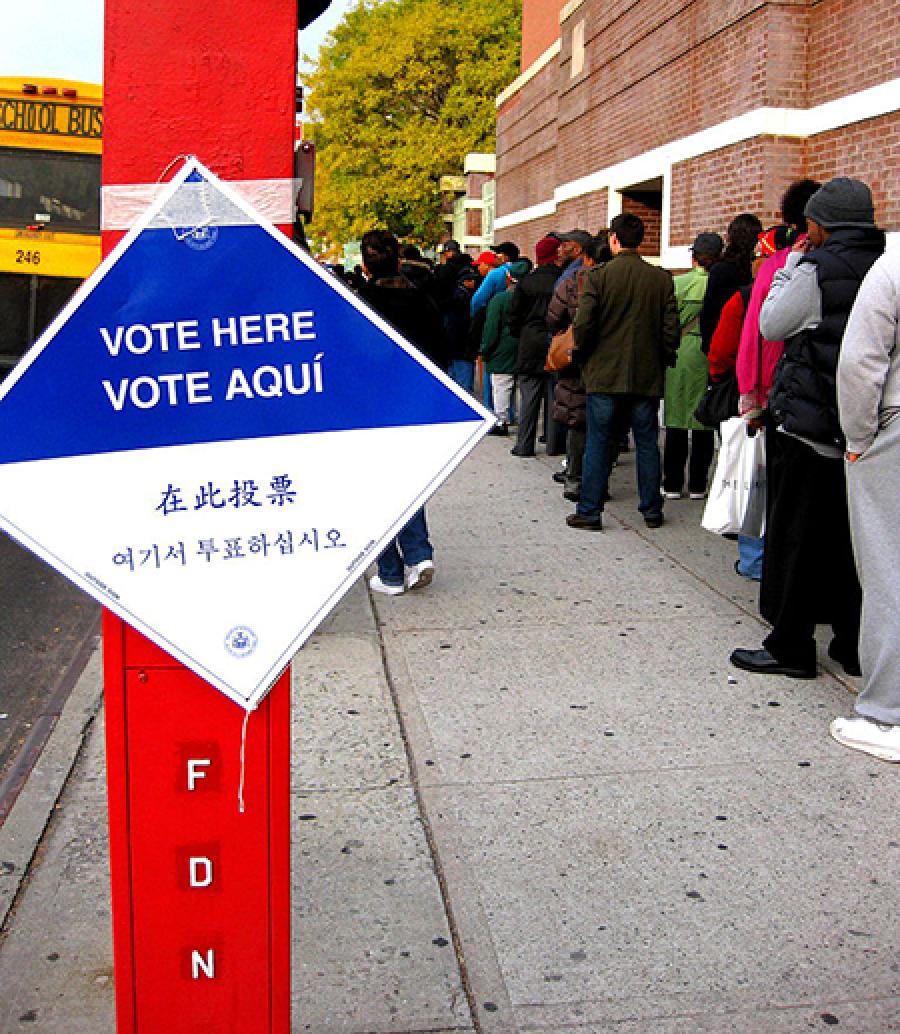 "Vote here" sign beside a line of people