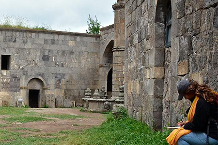 Person takes notes amidst old stone buildings