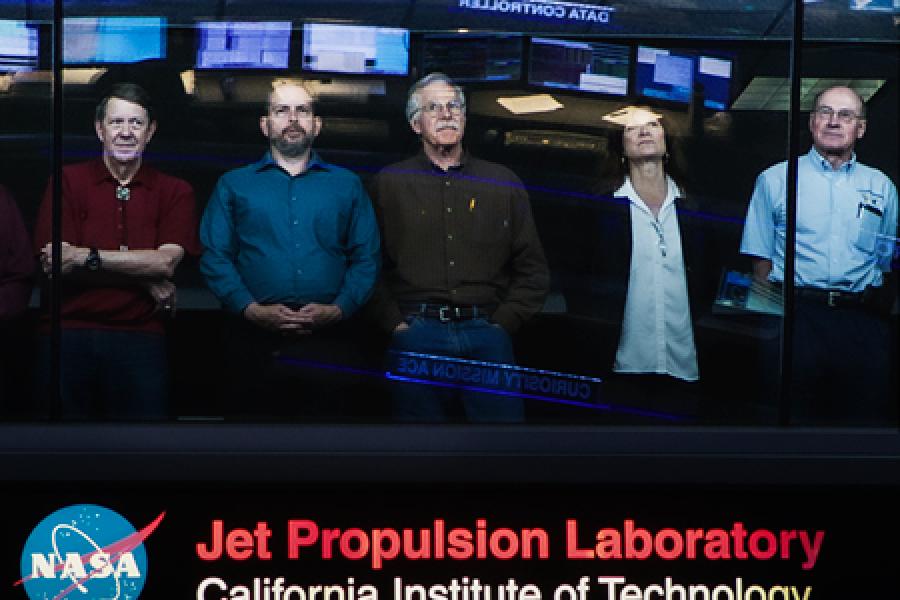 Cassini team leaders standing at a window, looking up.