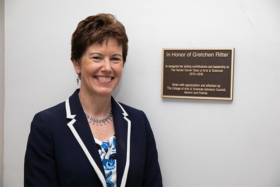 Gretchen Ritter stands by a plaque commemorating the Gretchen Ritter ‘83 First Generation Scholarship fund