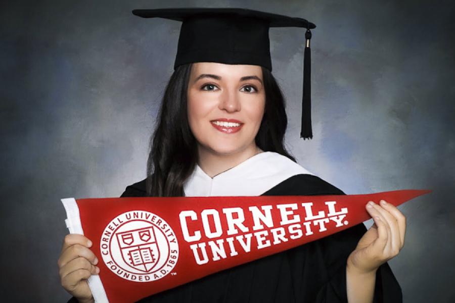 Edy Kennedy in cap and gown with Cornell banner