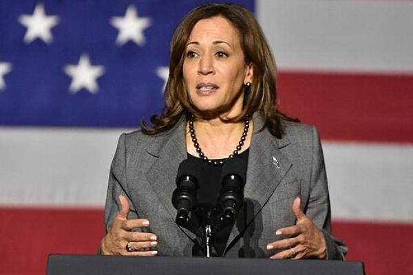 Kamala Harris at a podium with the seal of the vice president on it and an American flag in the background