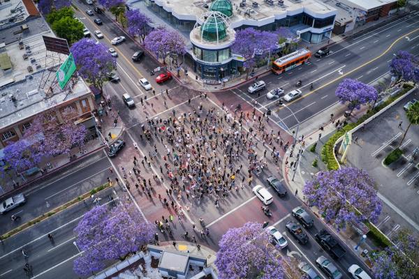 A crowd gathering on a city intersection, seen from above