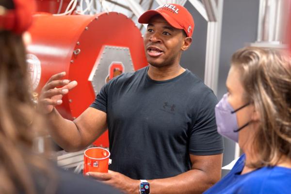 Person in Cornell cap speaks enthusiastically to a small group