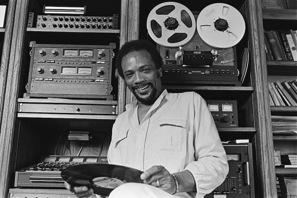 Person holding an LP in front of recording equipment in a studio