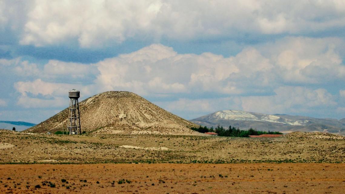 Dry landscape featuring a hill and partly cloudy sky