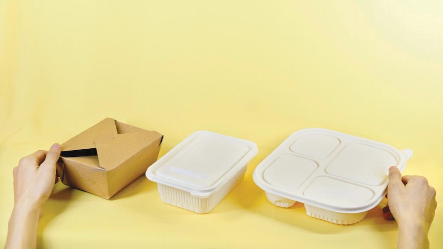 Three takeout food packages against a yellow background