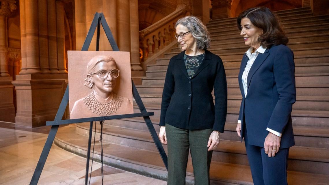 Two people look at a piece of art portraying the face of Ruth Bader Ginsburg