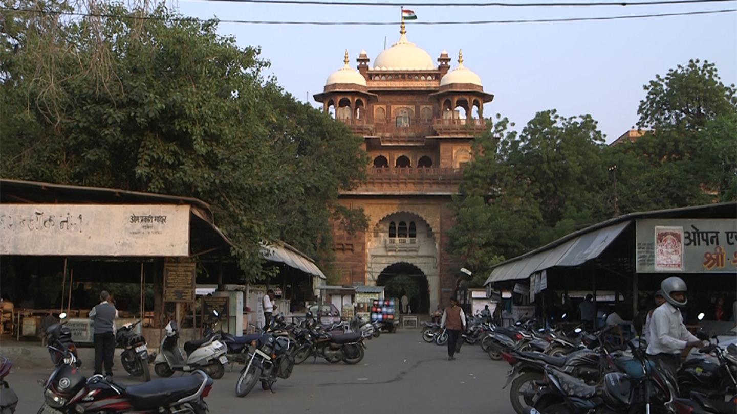 A gold building foregrounded by rows of stalls and many parked motorcycles