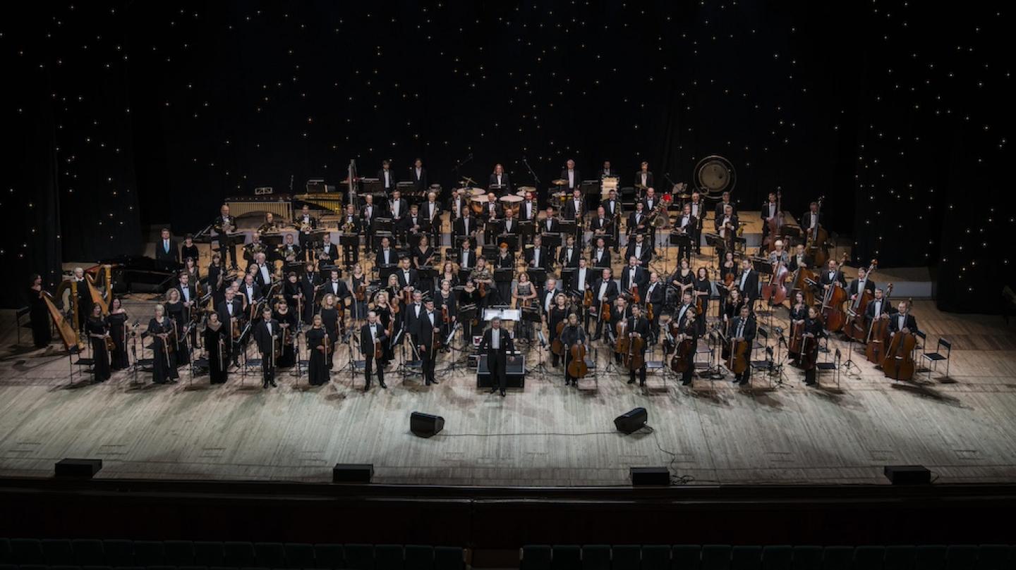 Looking down on a stage with a large orchestra arranged on it