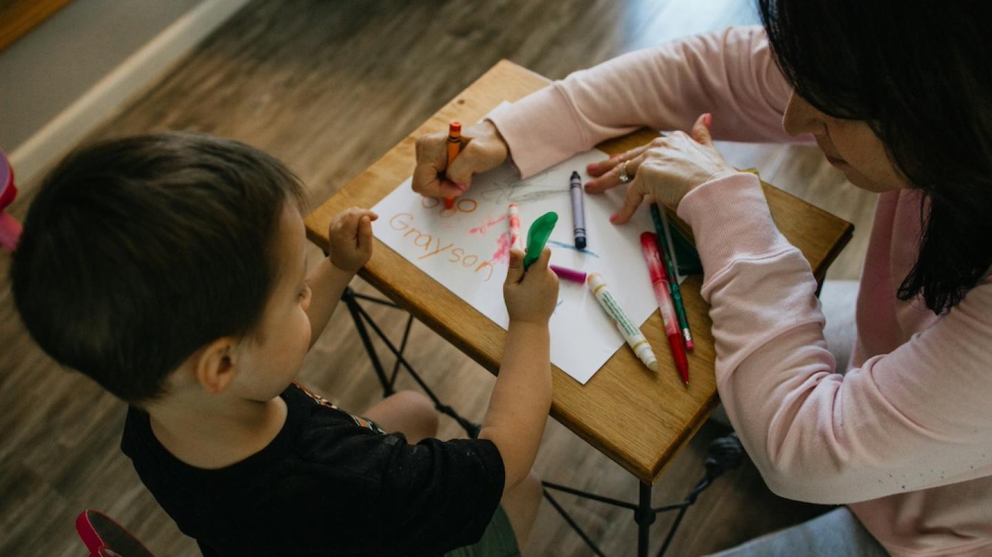 Two people color with markers at a small table