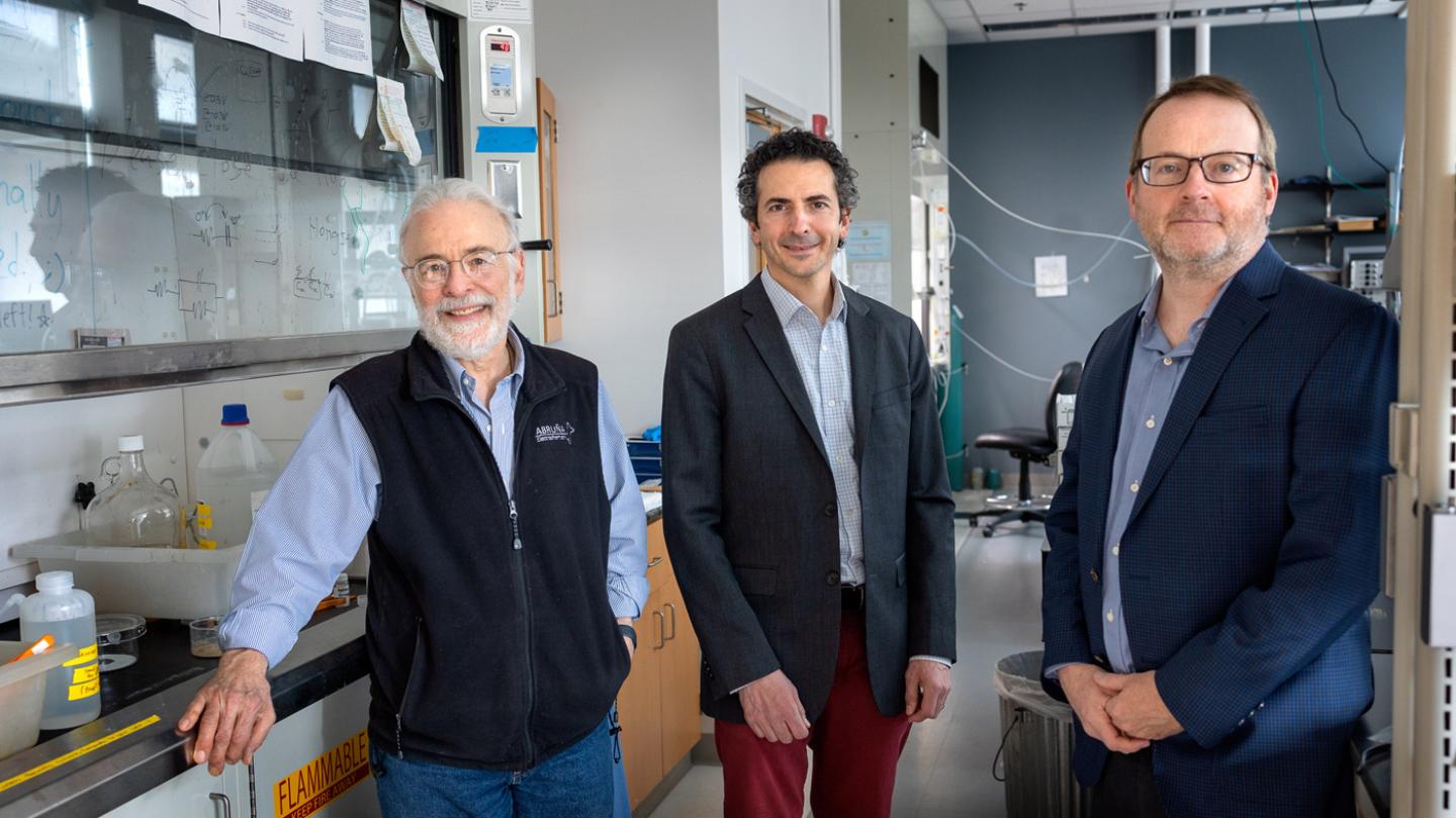 Three men standing in a chemistry laboratory