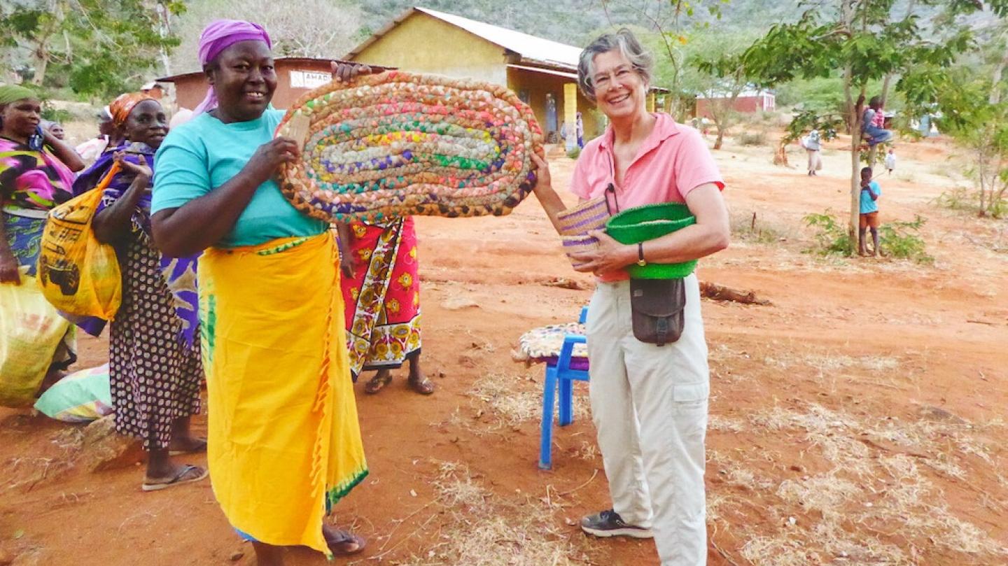 Two people holding a large, colorful basket between them