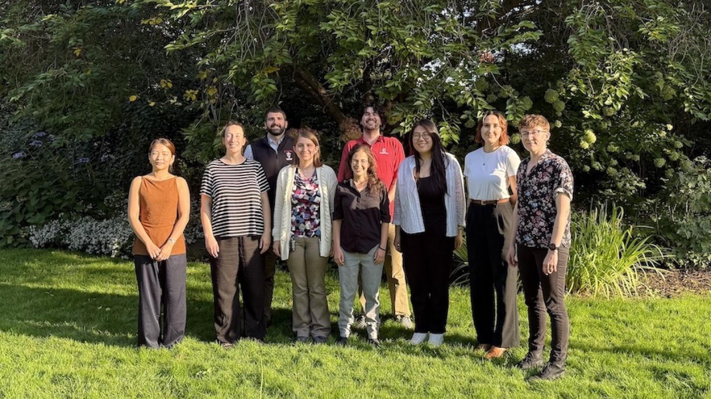 Nine people standing in a grassy area