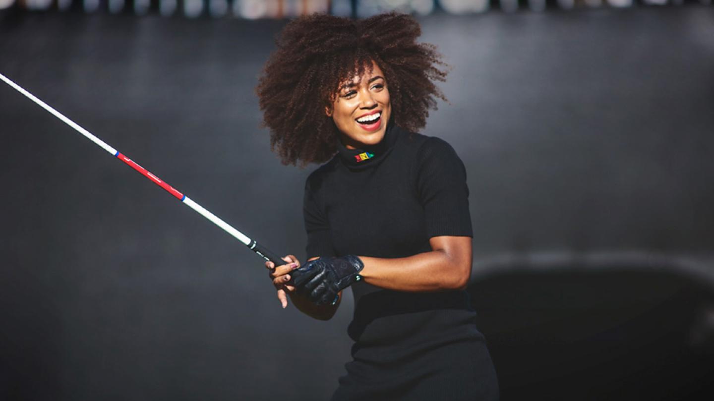 Person holding a golf club casually, smiling