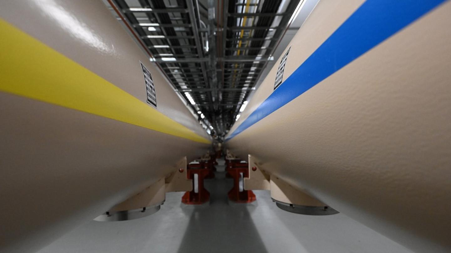 Close up of two very large tubes, the one on the left with a yellow stripe, the one on the right with a blue stripe
